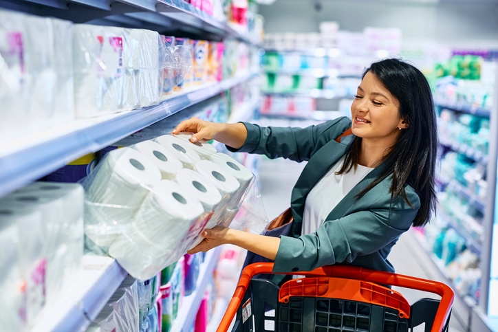Happy woman buying toilet paper in a supermarket.
